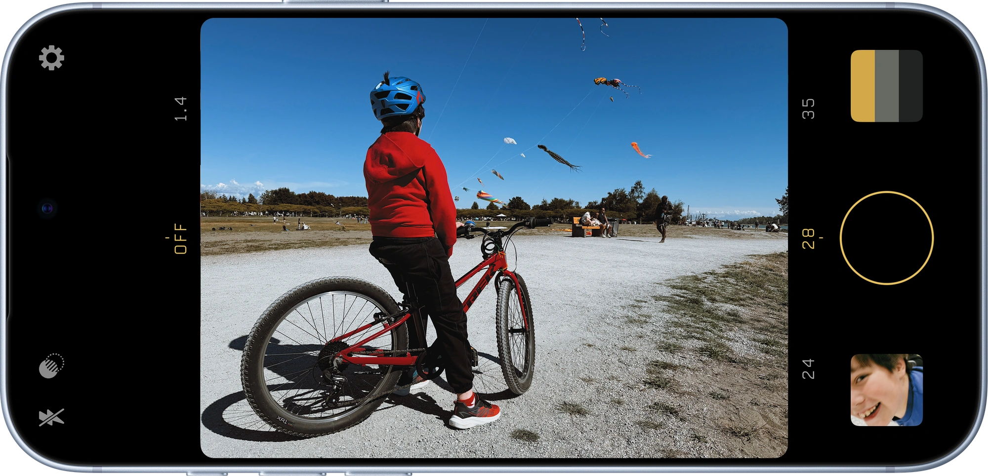 Filmpak on iPhone, framing a child with a bicycle beneath a sky full of kites
