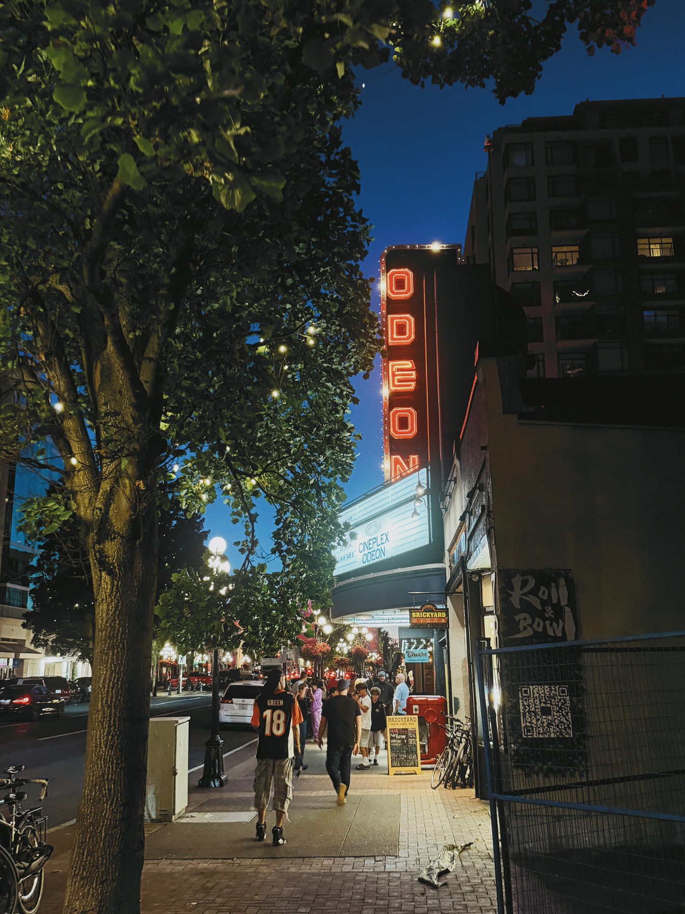 The Odeon cinema sign glowing above a tree-lined street at dusk, fading through black between focal lengths